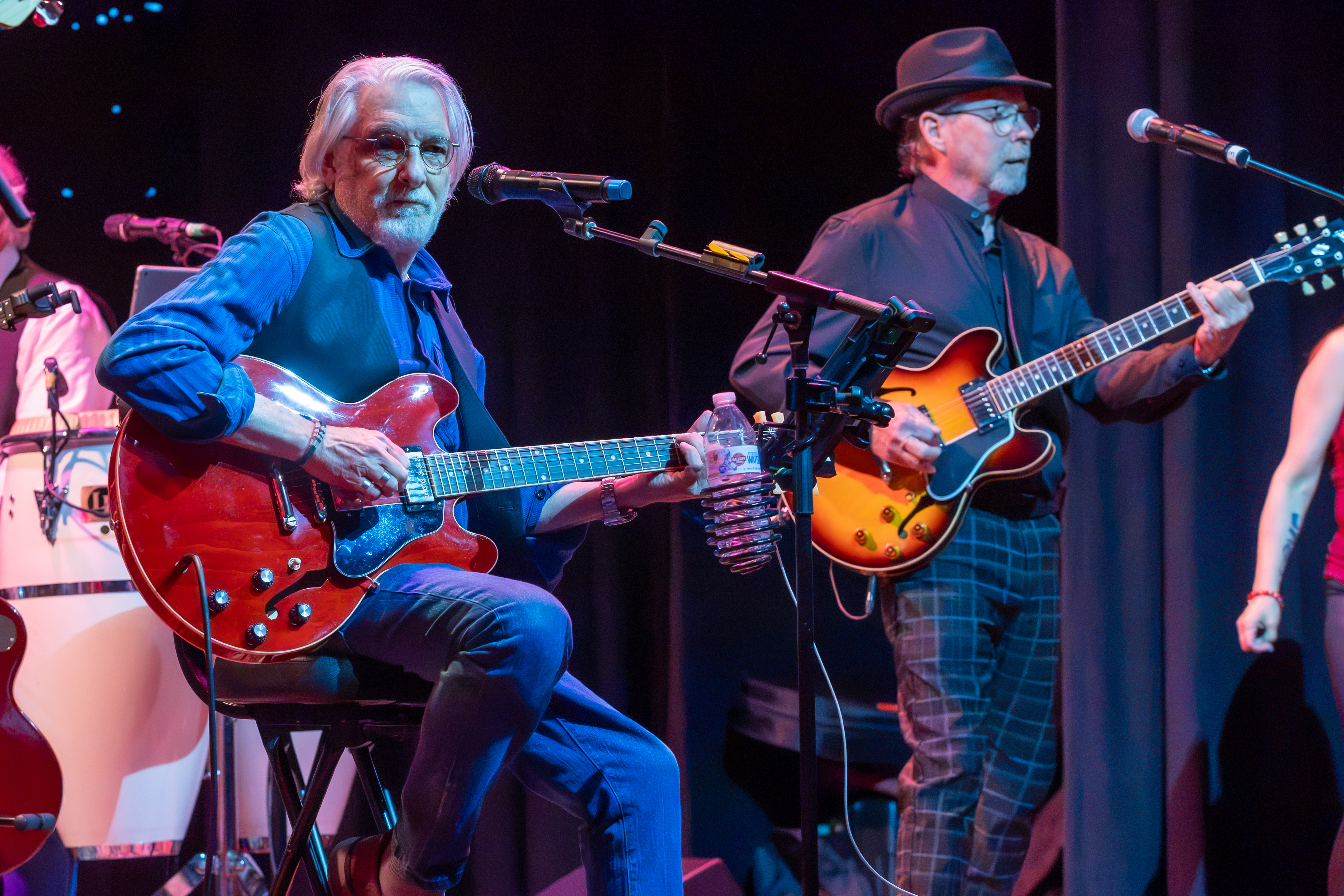 Guitarists trading licks on stage under blue and red lighting