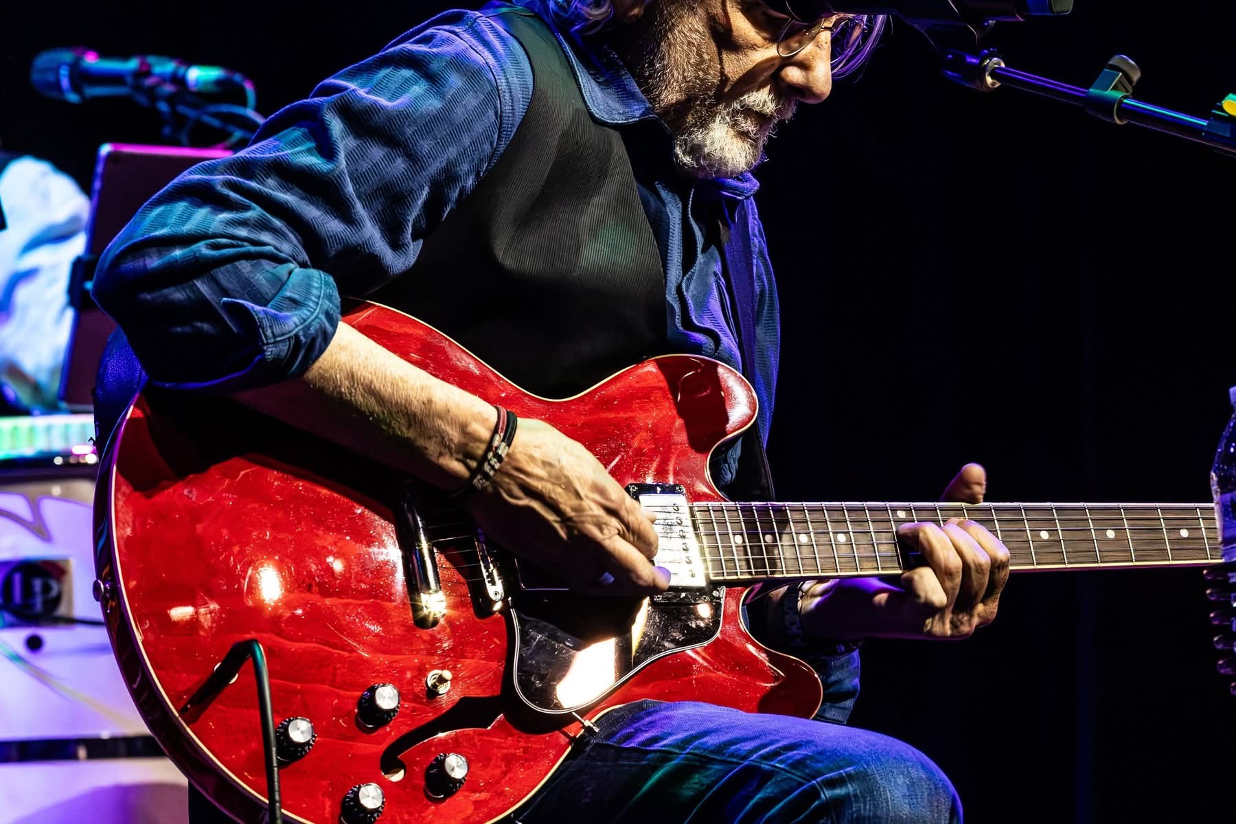 Close-up of hands playing a cherry red semi-hollow guitar