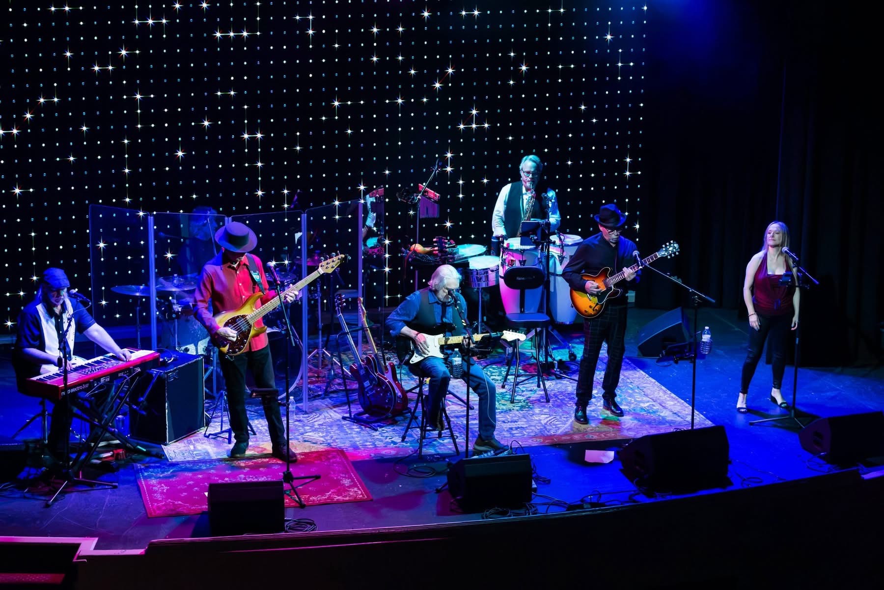 Full band performing on stage in front of a starlit backdrop